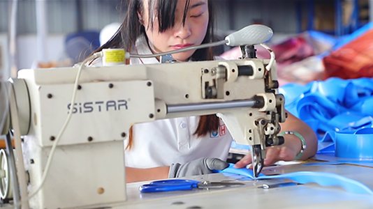 A manufacturing partner technician sewing blue inflatable material.